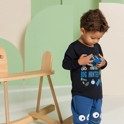 Criança com roupas de bebê e brincando